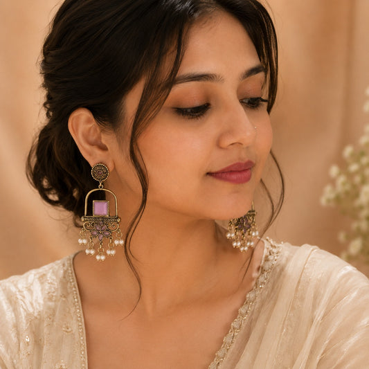 Model in an ivory tissue saree wearing antique gold drop earrings with a lilac stone and pearl clusters