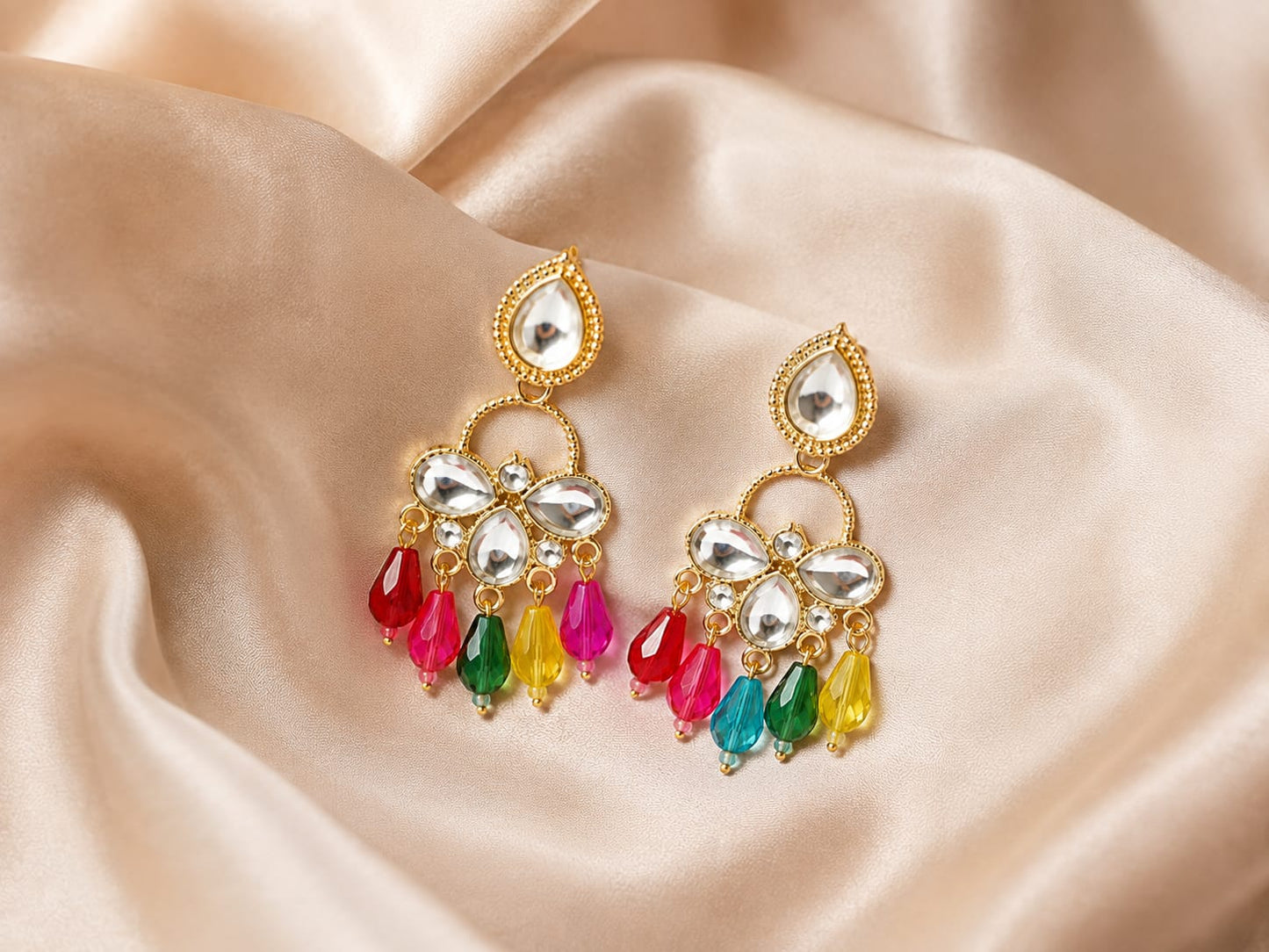 Gold-plated kundan chandelier earrings with red, pink, green and yellow bead drops on champagne satin