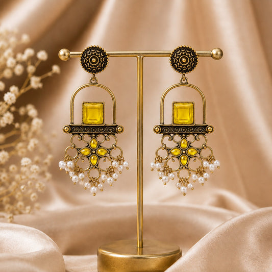 Antique gold arch drop earrings with a citrine yellow square stone, filigree apron and faux pearl clusters on a gold stand