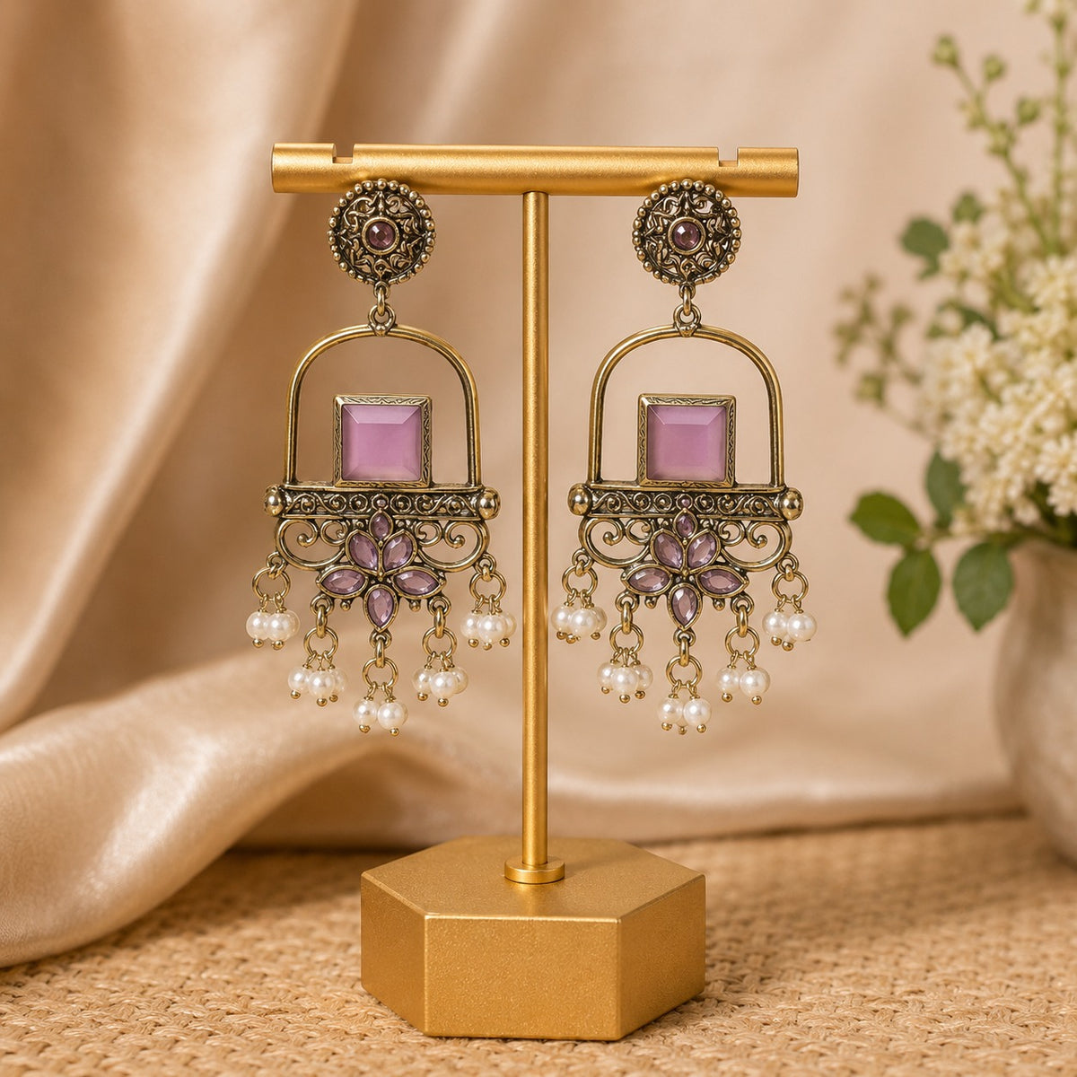 Antique gold arch drop earrings with a lilac square stone, filigree apron and faux pearl clusters on a gold stand