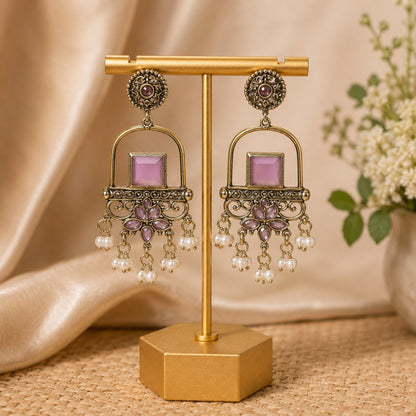 Antique gold arch drop earrings with a lilac square stone, filigree apron and faux pearl clusters on a gold stand