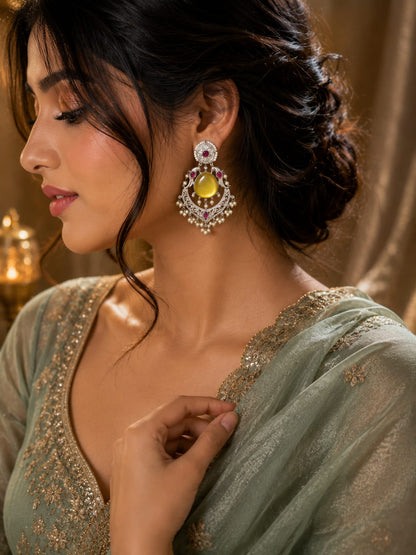 Model in a sage green embroidered saree wearing yellow cat's-eye oxidised chandbali earrings