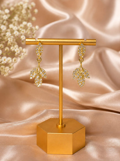 Gold-plated crystal leaf cluster drop earrings on a gold display stand against peach satin