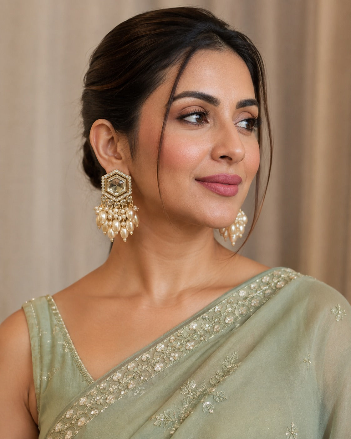 Model in a sage green saree wearing gold hexagon crystal studs with an oval faux pearl cluster