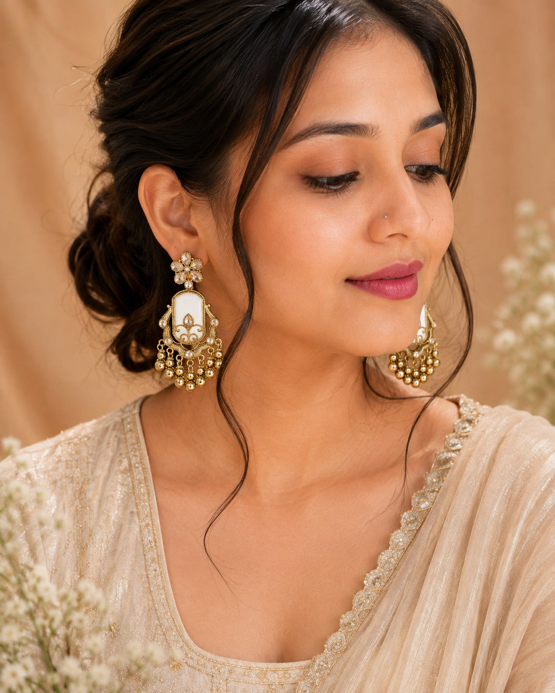 Model in an ivory embroidered saree wearing gold chandbali earrings with an ivory panel and gold bead fringe