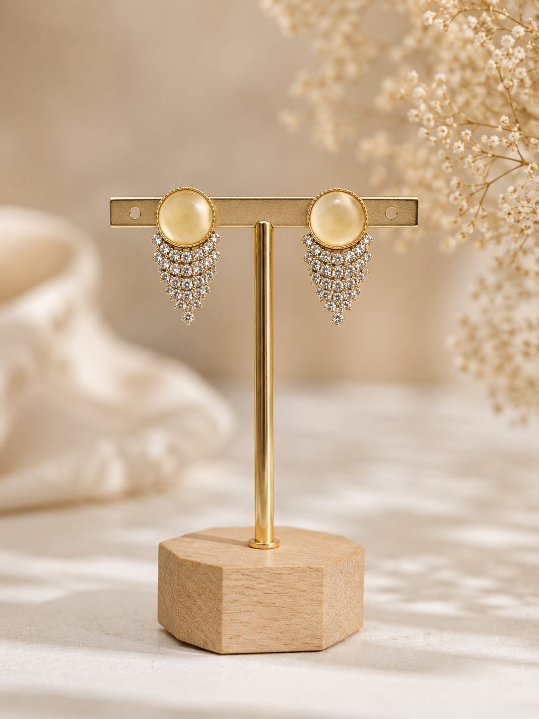 Gold-plated stud earrings with a yellow cat's-eye cabochon and a chevron fringe of clear crystals