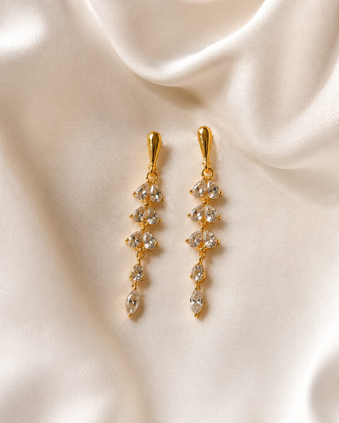 Gold-plated long drop earrings with five tiers of pear-cut clear crystals on ivory satin