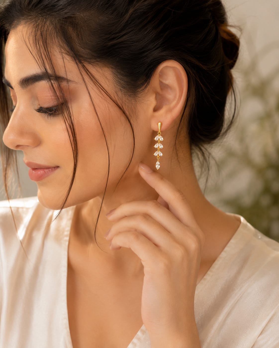 Model in a cream satin shirt wearing a gold crystal cascade drop earring
