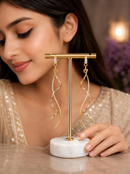 Model in an ivory sequinned saree beside gold-plated spiral drop earrings on a marble stand