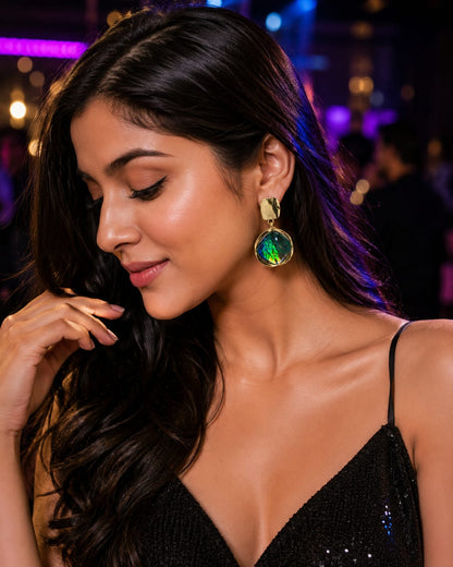 Model in a black sequinned dress wearing iridescent green glass drop earrings at a party