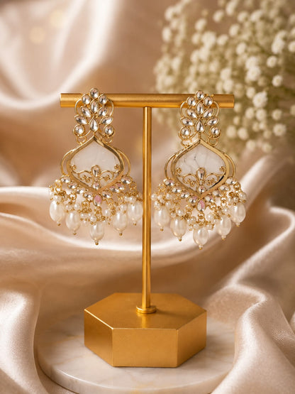 Gold-plated kundan chandbali earrings with an ivory centre stone and a pearl fringe on a gold display stand