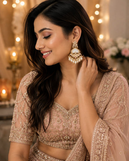 Model in a peach embroidered lehenga wearing ivory kundan chandbali earrings with pearl drops