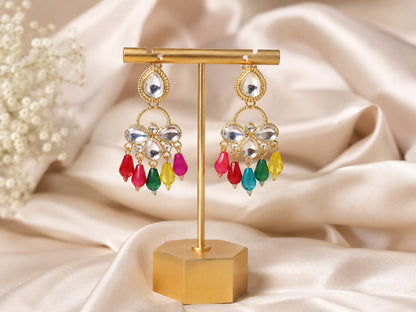 Gold-plated kundan chandelier earrings with multicolour glass bead drops on a gold stand against cream satin