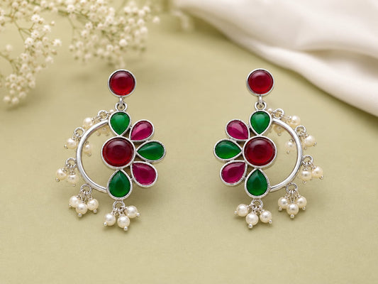 Ruby and emerald kundan floral chandbali earrings with pearl clusters on a sage green background
