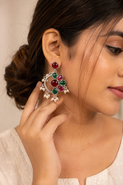 Model with a pearl-strung bun wearing a ruby and emerald kundan chandbali earring