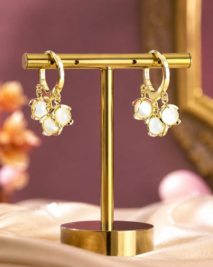 Gold-plated huggie hoop earrings with a cluster of three white moonstone cabochons on a gold stand