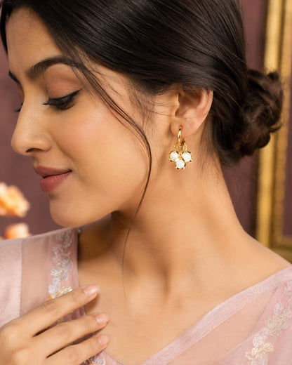 Model in a blush pink saree wearing gold huggie hoops with white stone clusters