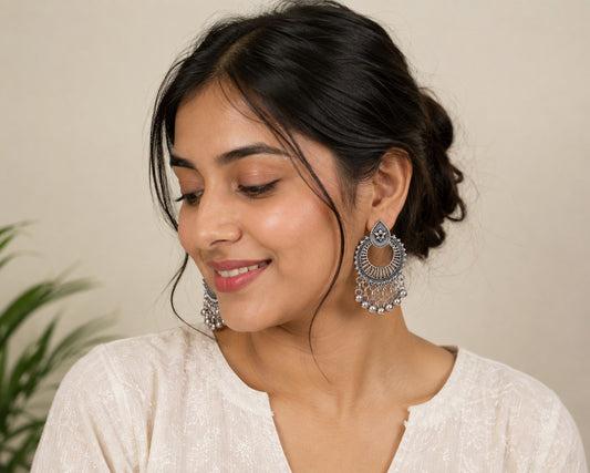 Model in a white chikankari kurta wearing oxidised chand bali earrings with a silver bell fringe