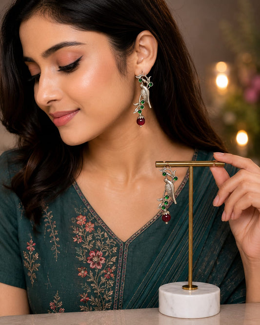 Model in a green embroidered kurta wearing oxidised silver parrot earrings with green stones and a maroon drop