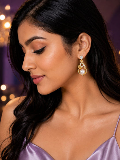 Model in a lilac satin dress wearing gold pearl heart earrings with a crystal solitaire stud top