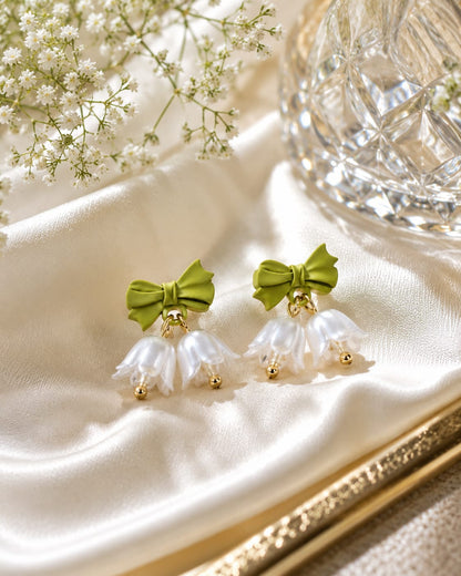 Close view of green bow studs with white pearl bell flowers and gold bead tips