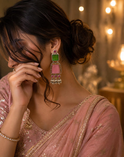 Model in a rose pink saree wearing green and rose pink oxidised stone drop earrings